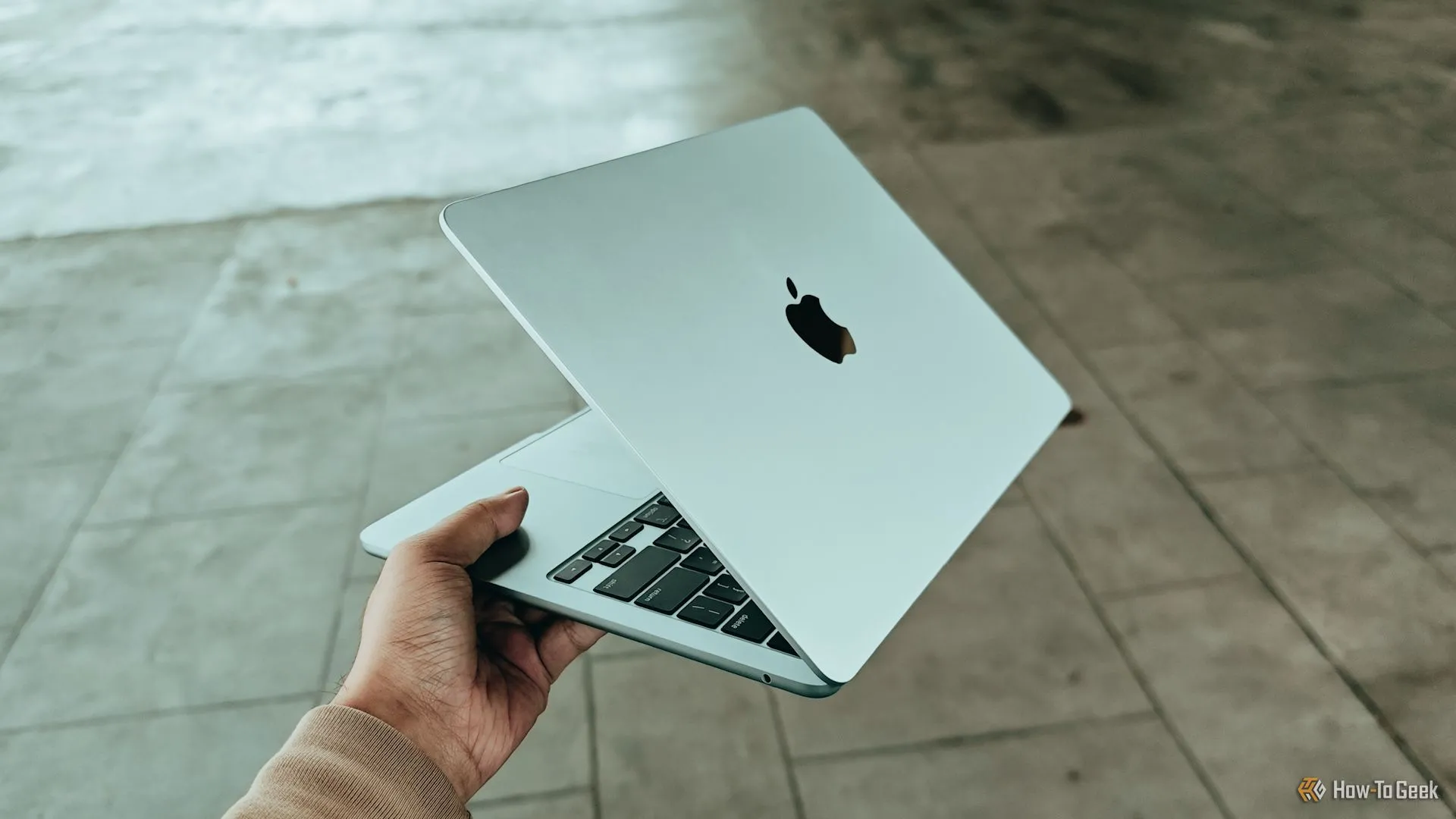 Bàn tay giữ chiếc MacBook Air với chip M4, tượng trưng cho nhu cầu kết nối di động trên laptop Apple