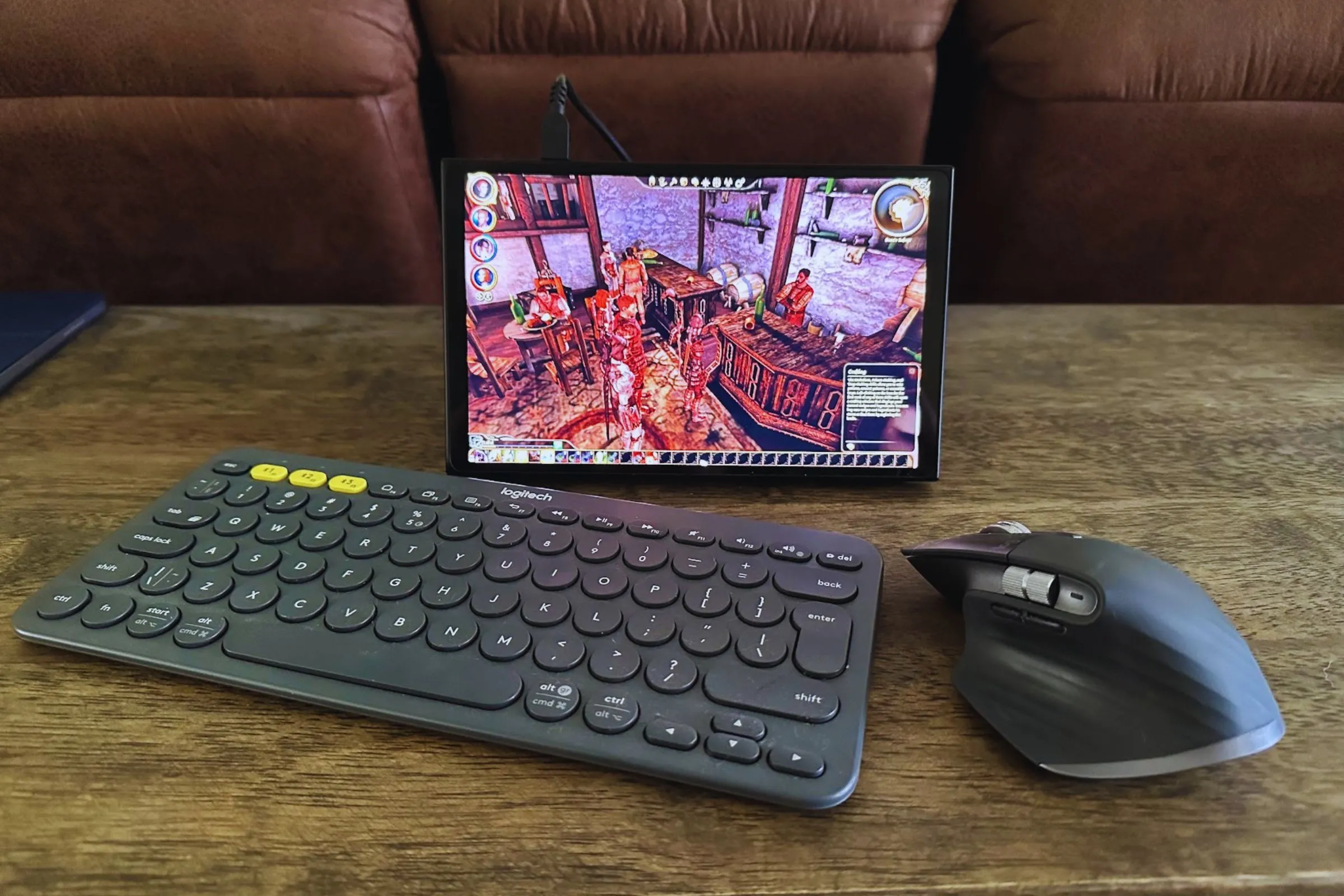 Bộ ba thiết bị làm việc gồm bàn phím Logitech K380, chuột MX Master 3S và PC cầm tay Lenovo Legion Go trên bàn gỗ.