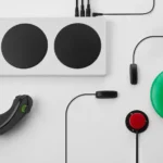 Bộ điều khiển Xbox Adaptive Controller kết nối với cần điều khiển, nút bấm lớn và các phụ kiện hỗ trợ qua cổng 3.5mm.