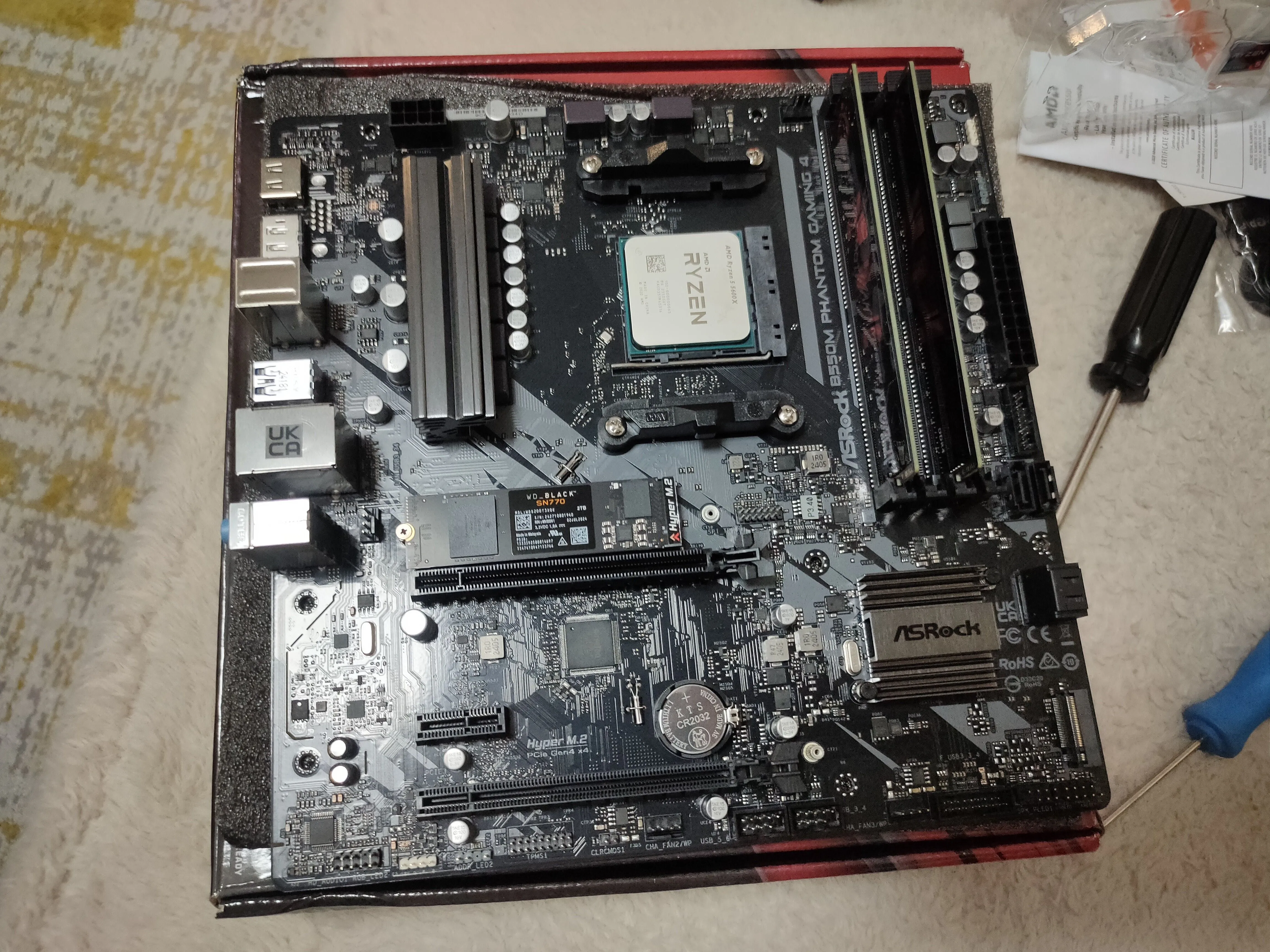 Bo mạch chủ đặt trên vỏ hộp cùng CPU và RAM đã được lắp đặt, sẵn sàng cho bước kiểm tra ban đầu.