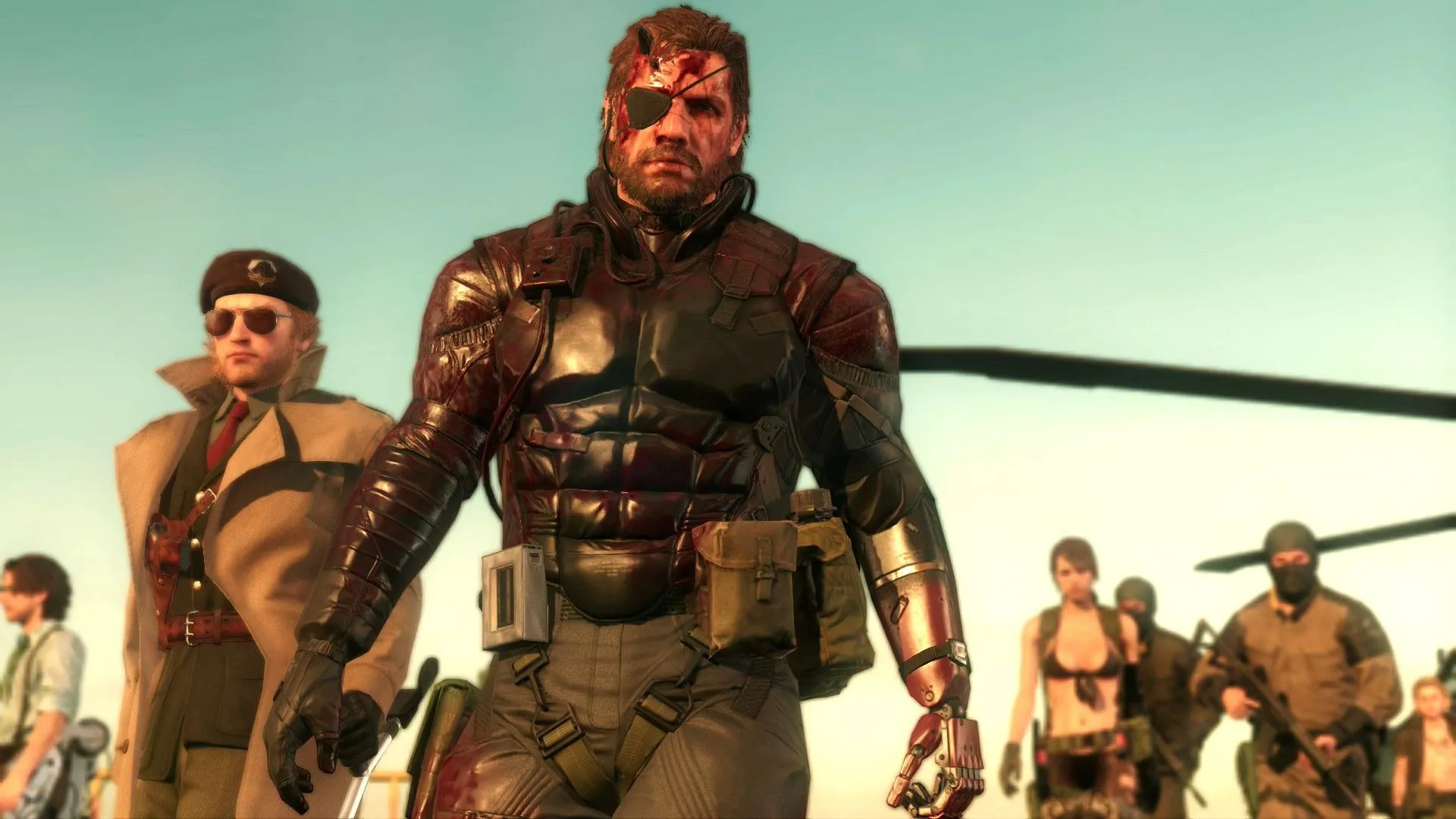 Các nhân vật Huey Emmerich, Kazuhira Miller, Venom Snake và Quiet cùng binh lính nhìn vào màn hình trong Metal Gear Solid V: The Phantom Pain, thể hiện bối cảnh game và đội ngũ nhân sự Kojima Productions.