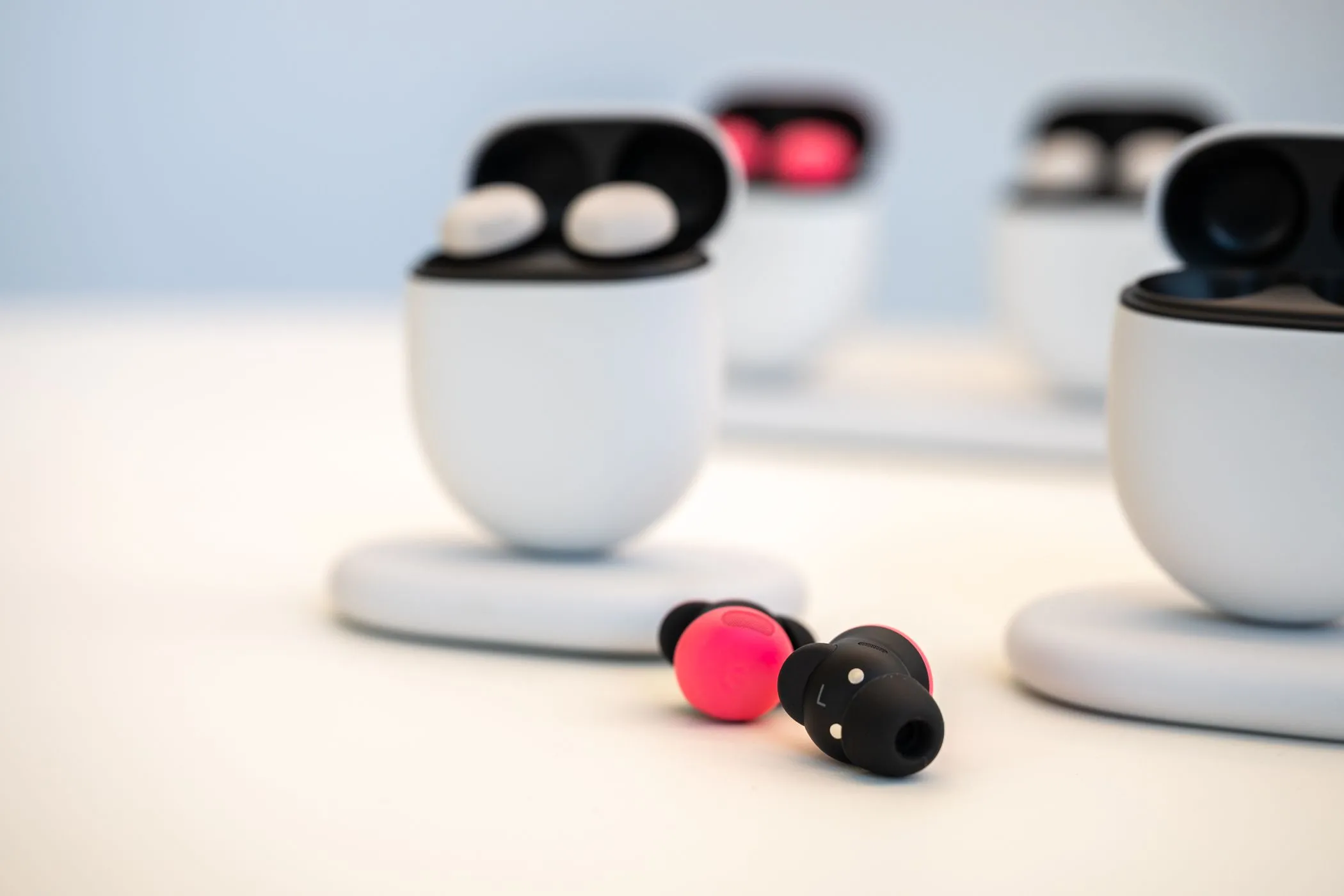 Cặp tai nghe Google Pixel Buds Pro 2 màu Peony đặt trên bàn, tách rời khỏi hộp sạc