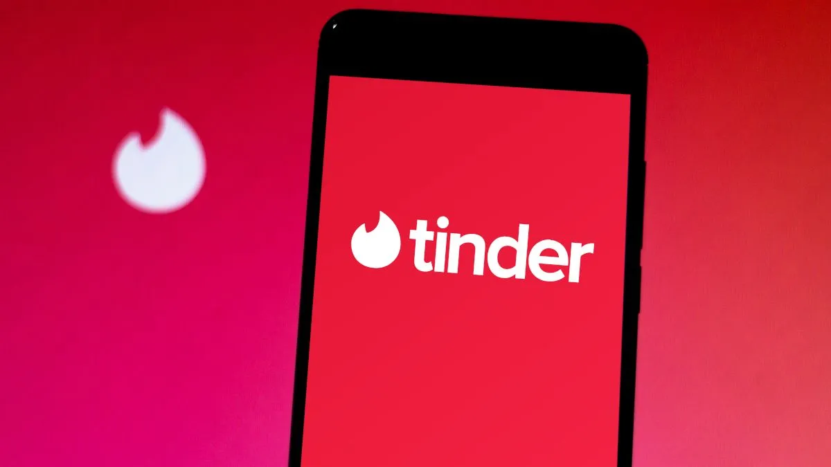 Điện thoại thông minh hiển thị logo ứng dụng Tinder trên nền đỏ, minh họa về hẹn hò trực tuyến.