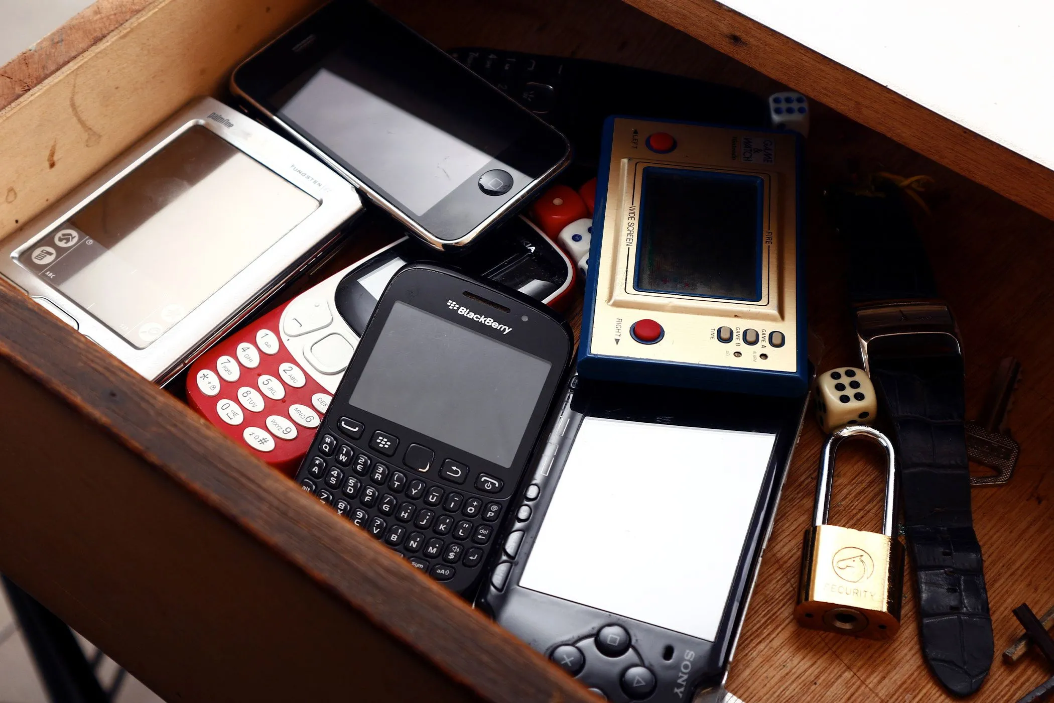 Điện thoại và console game cũ chất đống trong ngăn kéo, gợi nhắc việc tái chế thiết bị điện tử.