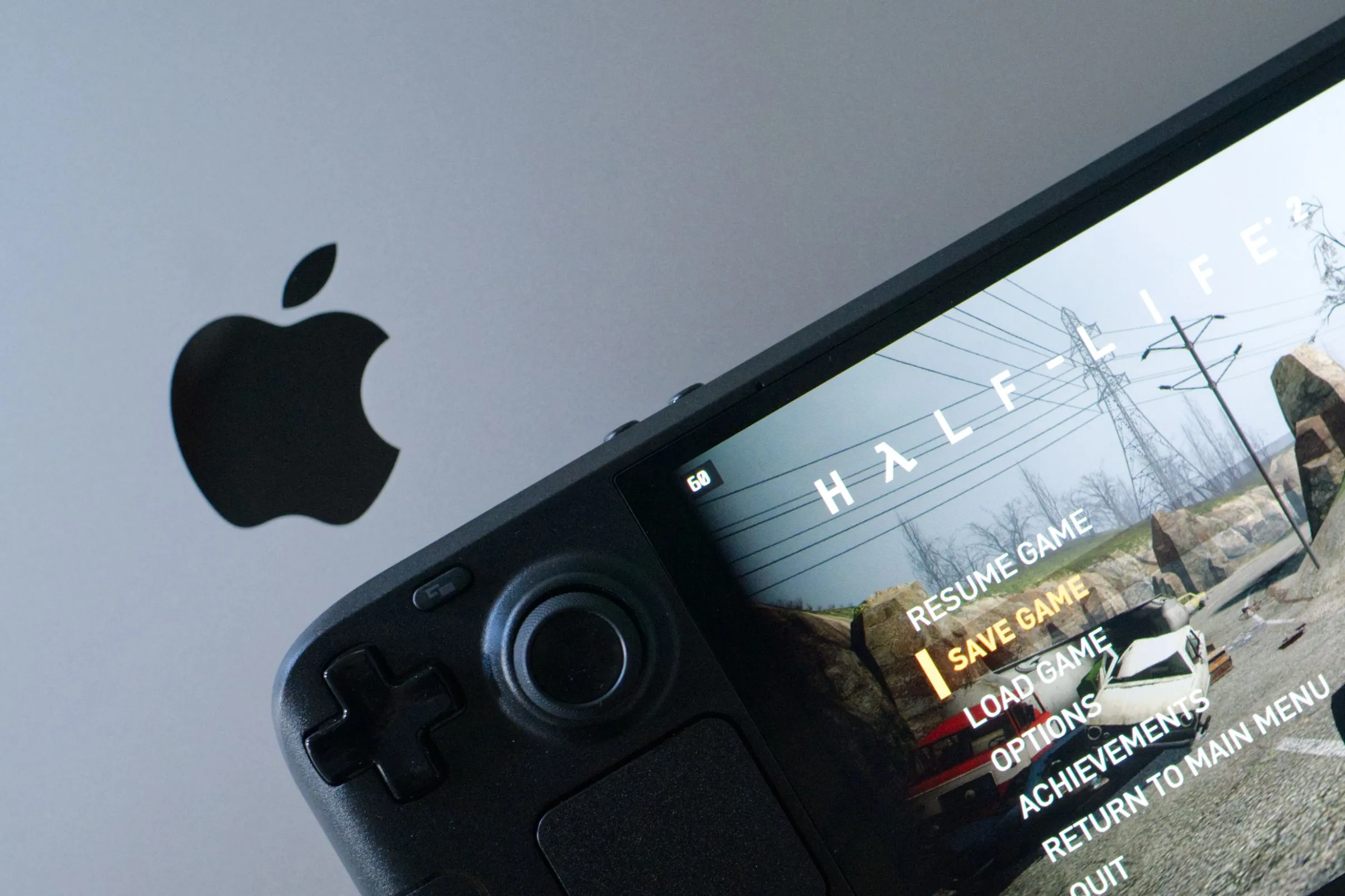 Hình ảnh chiếc Steam Deck OLED hiển thị game Half-Life 2 đặt cạnh MacBook Pro, minh họa sự đa dạng của thiết bị chơi game cá nhân.