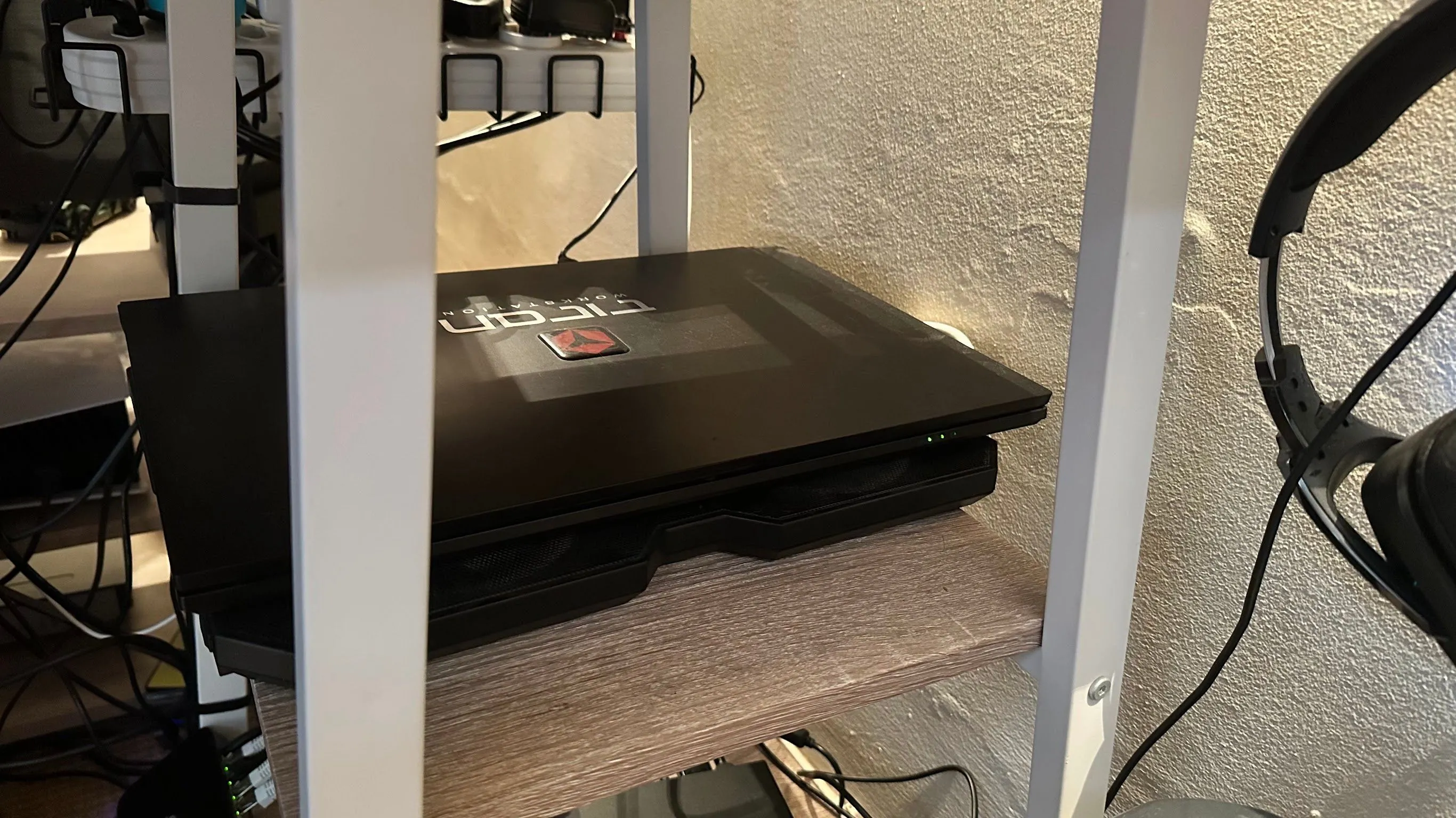 Laptop đóng nắp đặt trên đế tản nhiệt, gọn gàng trong ngăn kéo bàn làm việc, tối ưu không gian.