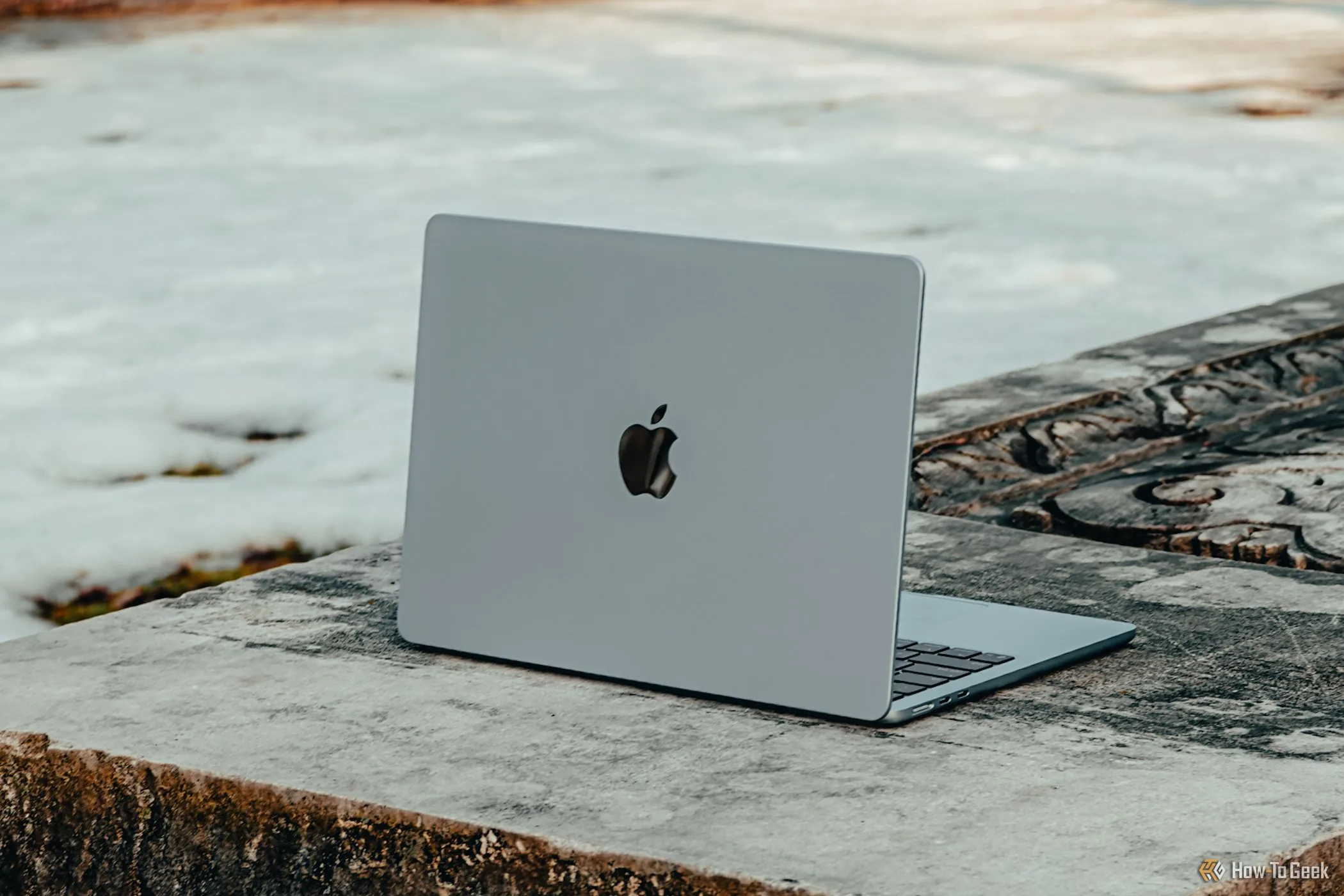 Laptop MacBook Air M4 màu xanh dương nhạt đặt trên bề mặt bê tông, nhìn từ góc chéo