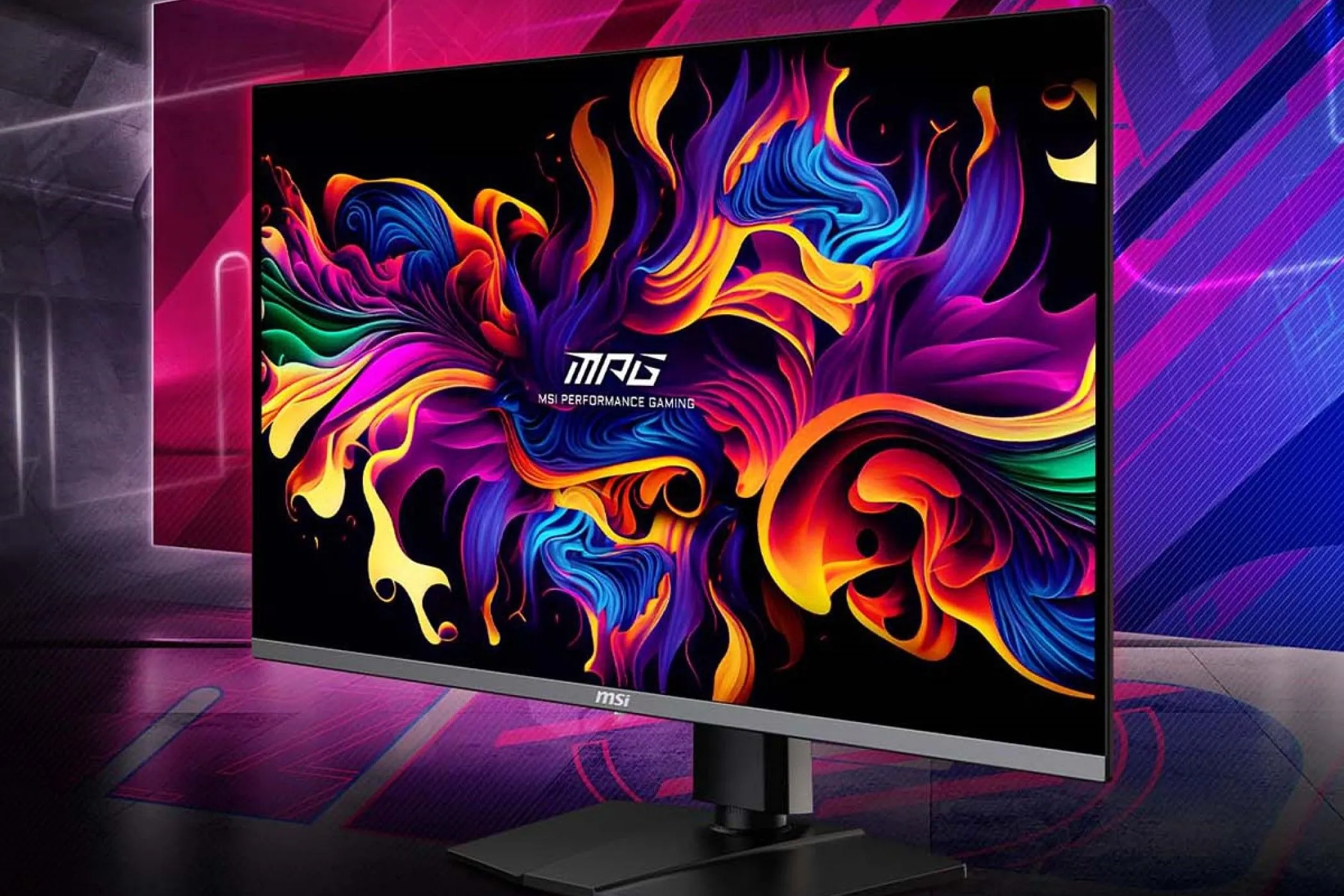 Màn hình MSI MPG321URX trên bàn làm việc với phông nền đa màu