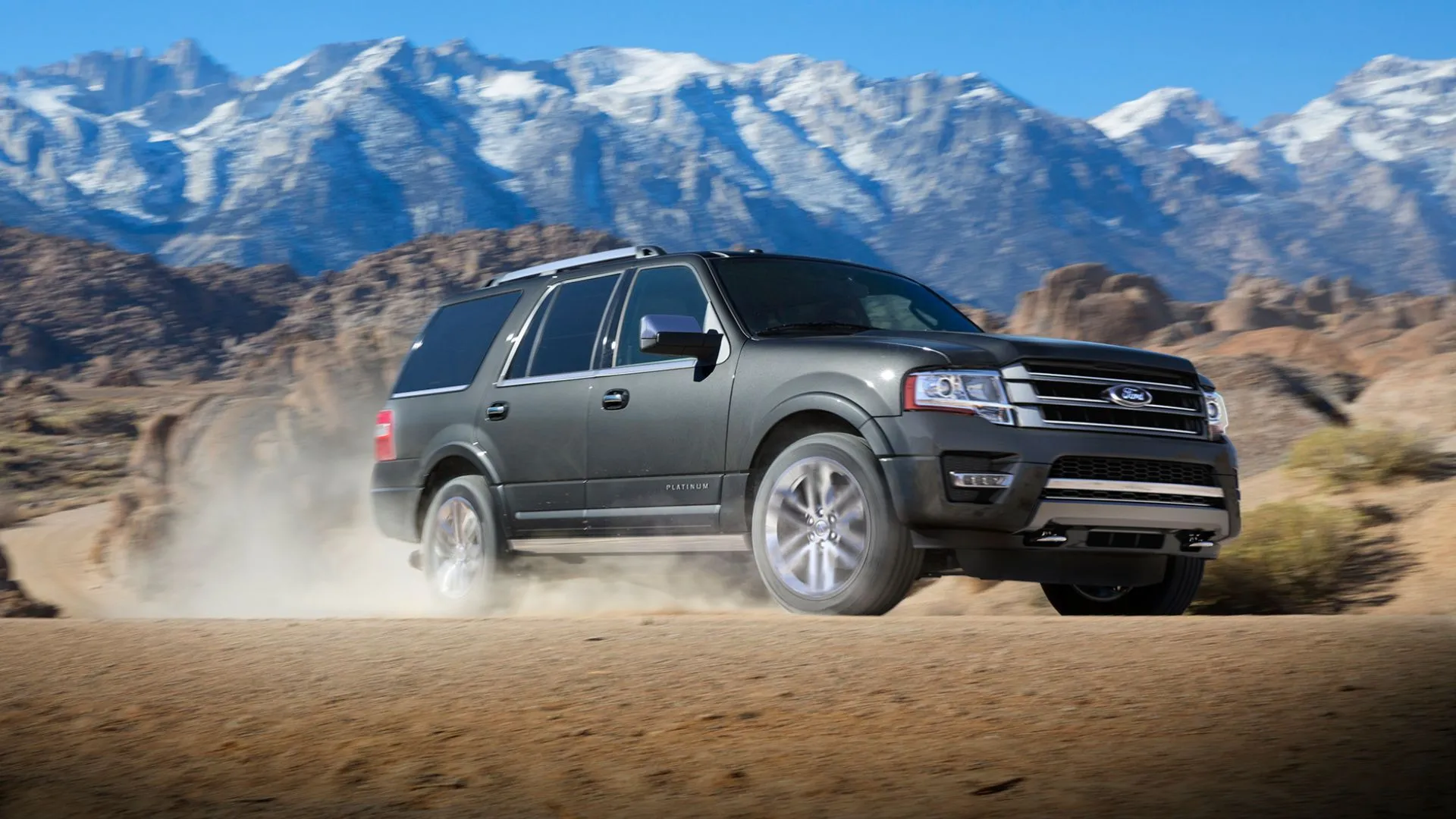 Mẫu SUV Ford Expedition 2017 màu xám đang vượt địa hình cát, thể hiện khả năng vận hành của dòng xe Ford.