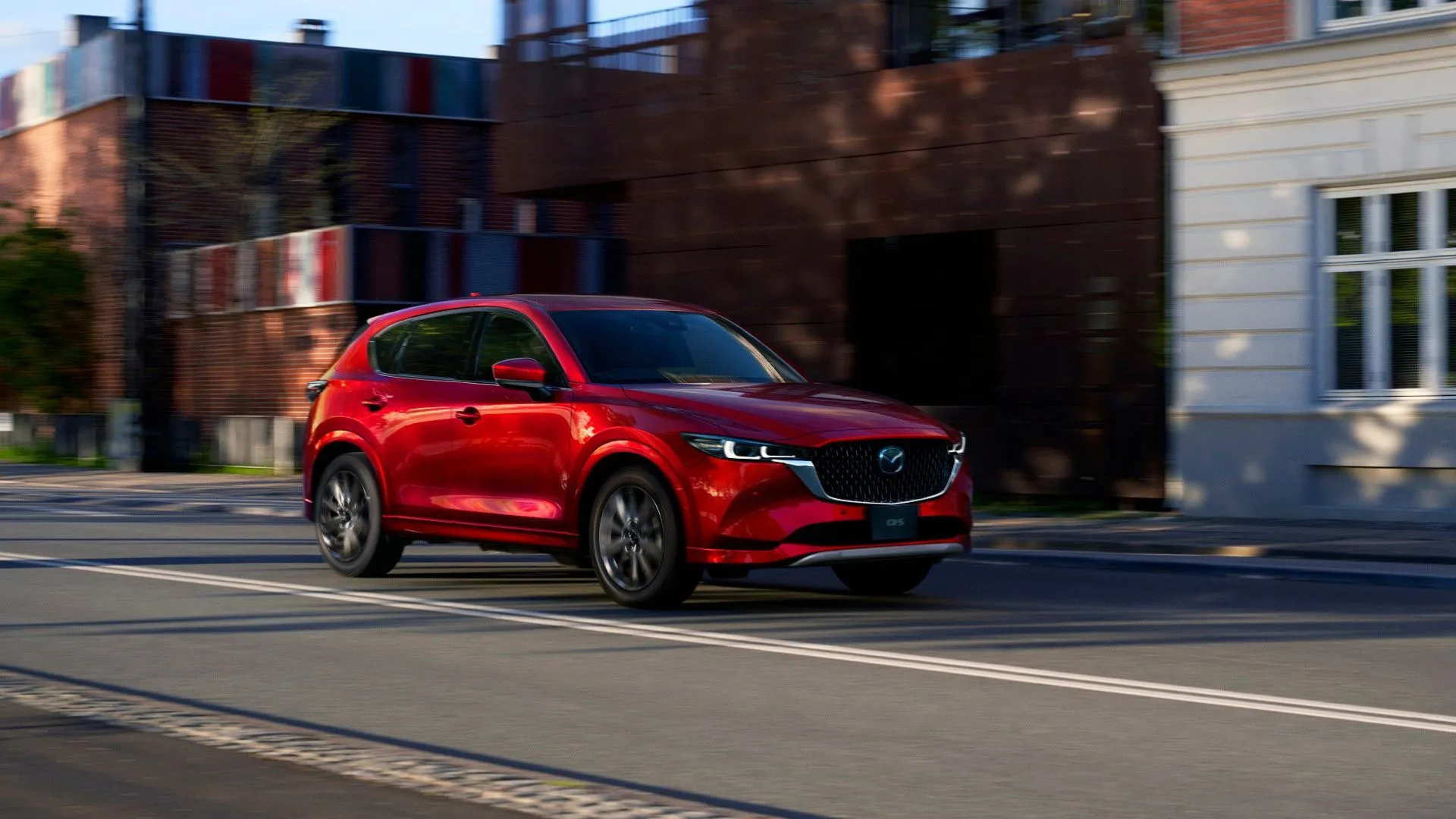 Mẫu SUV Mazda CX-5 thế hệ mới màu trắng bạc, đỗ trên nền tối, nhìn từ góc thấp