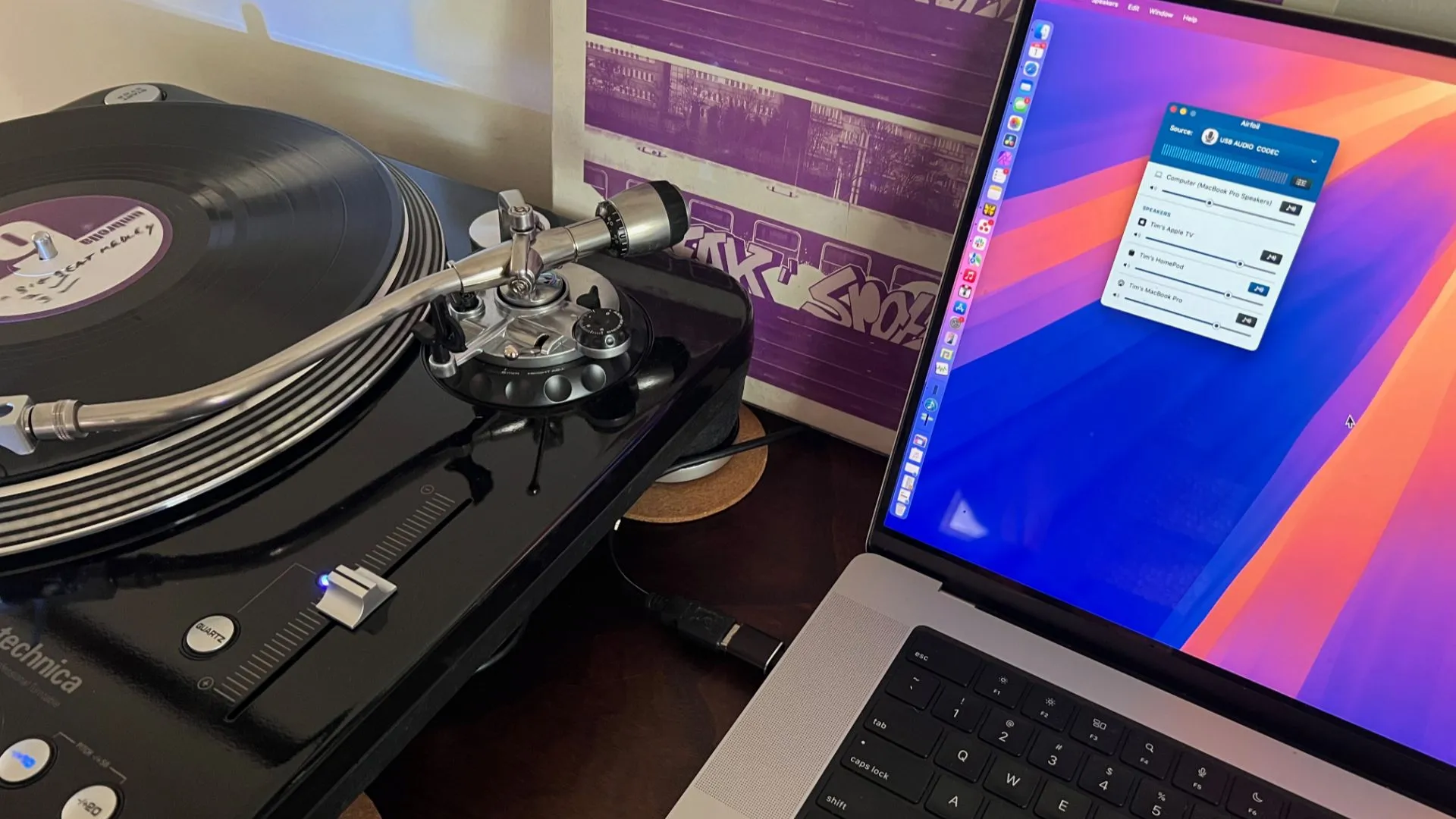 Máy MacBook Pro kết nối với bàn xoay đĩa than, đang phát nhạc từ đĩa vinyl qua hệ thống không dây.
