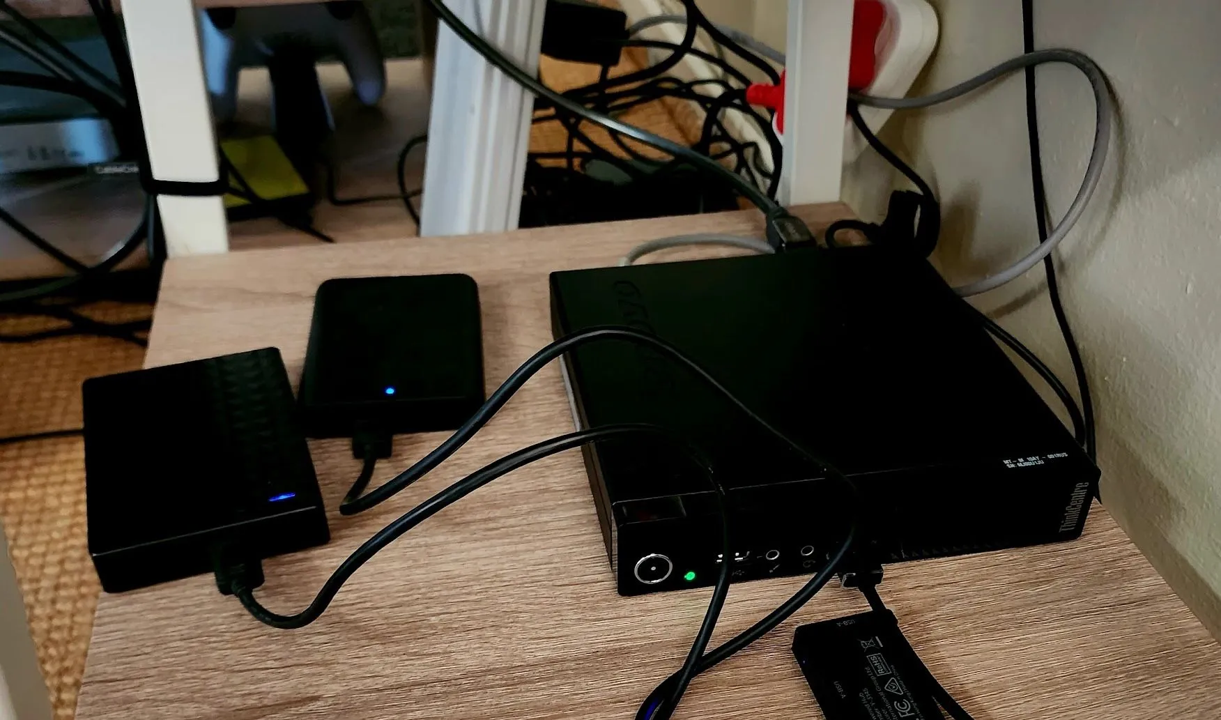 Máy tính mini Plex server với nhiều ổ USB ngoài, đặt gọn gàng trên kệ bàn.