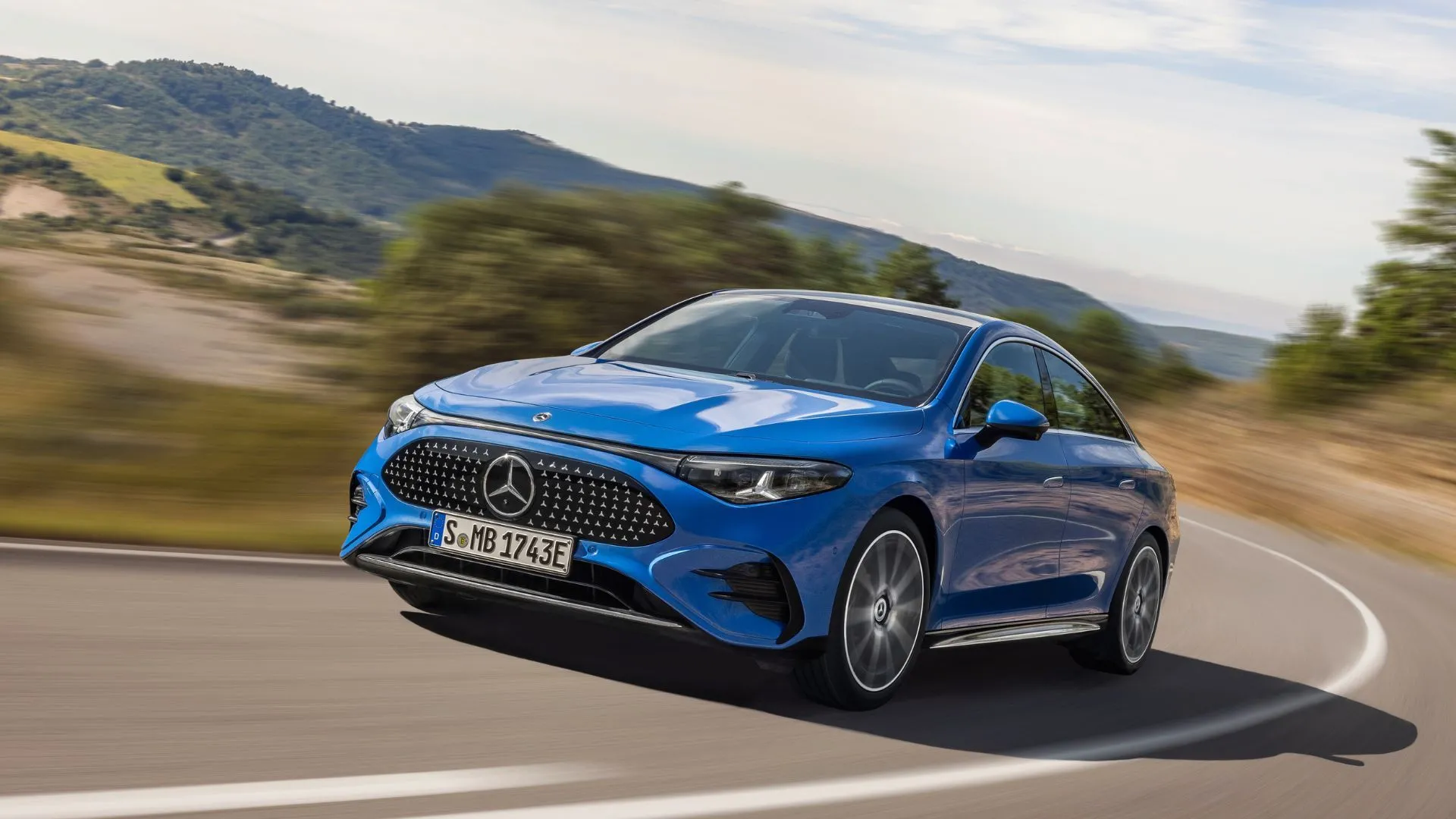 Mercedes-Benz CLA 2026 màu xanh đang di chuyển trên đường đồi, thể hiện sự tiện lợi của hệ thống giải trí Disney+ trong các chuyến đi dài.