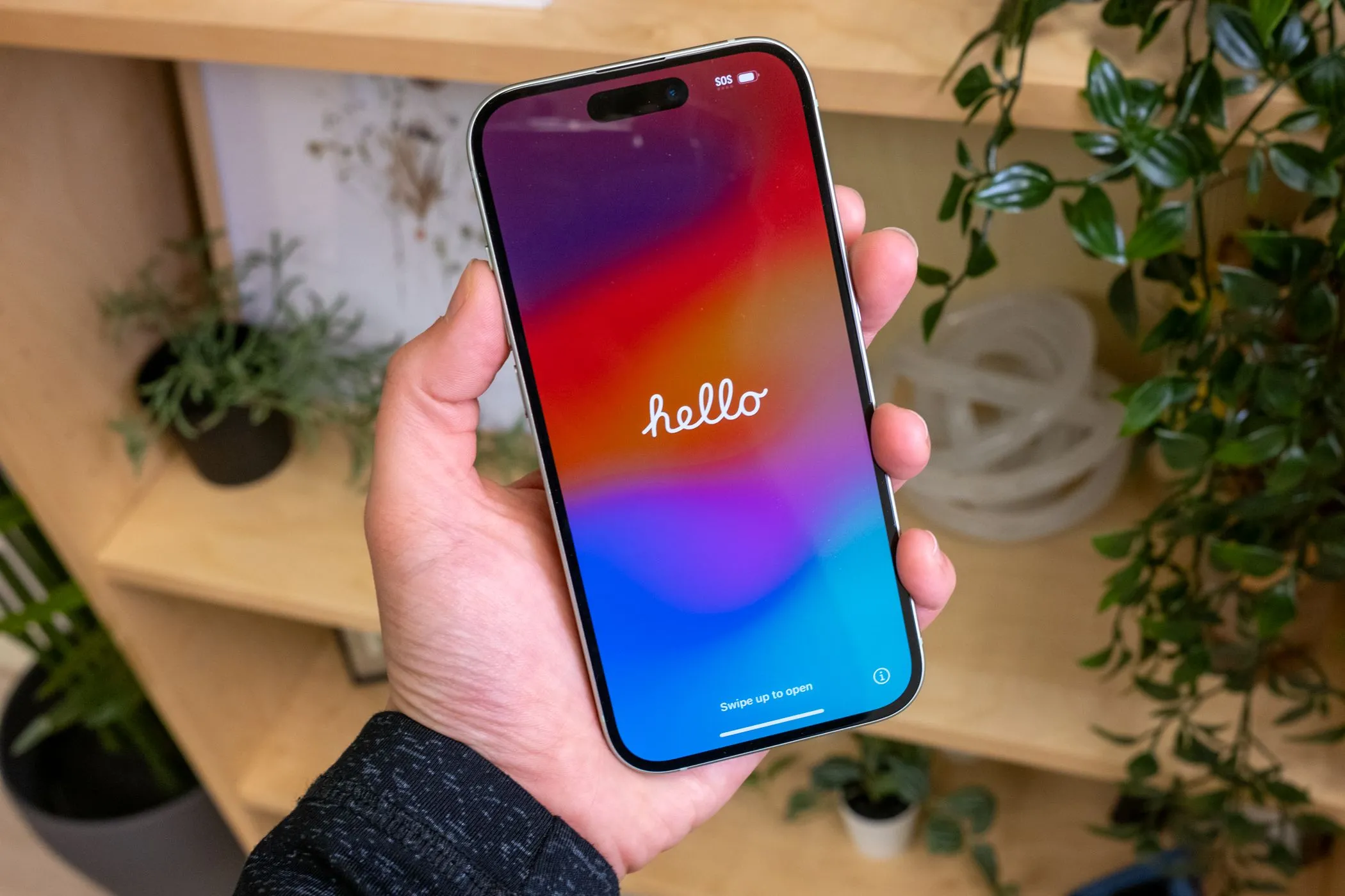 Một người đang cầm chiếc iPhone 15 màu xanh lá cây với màn hình hiển thị nội dung, làm nổi bật chất lượng hiển thị Super Retina XDR OLED.