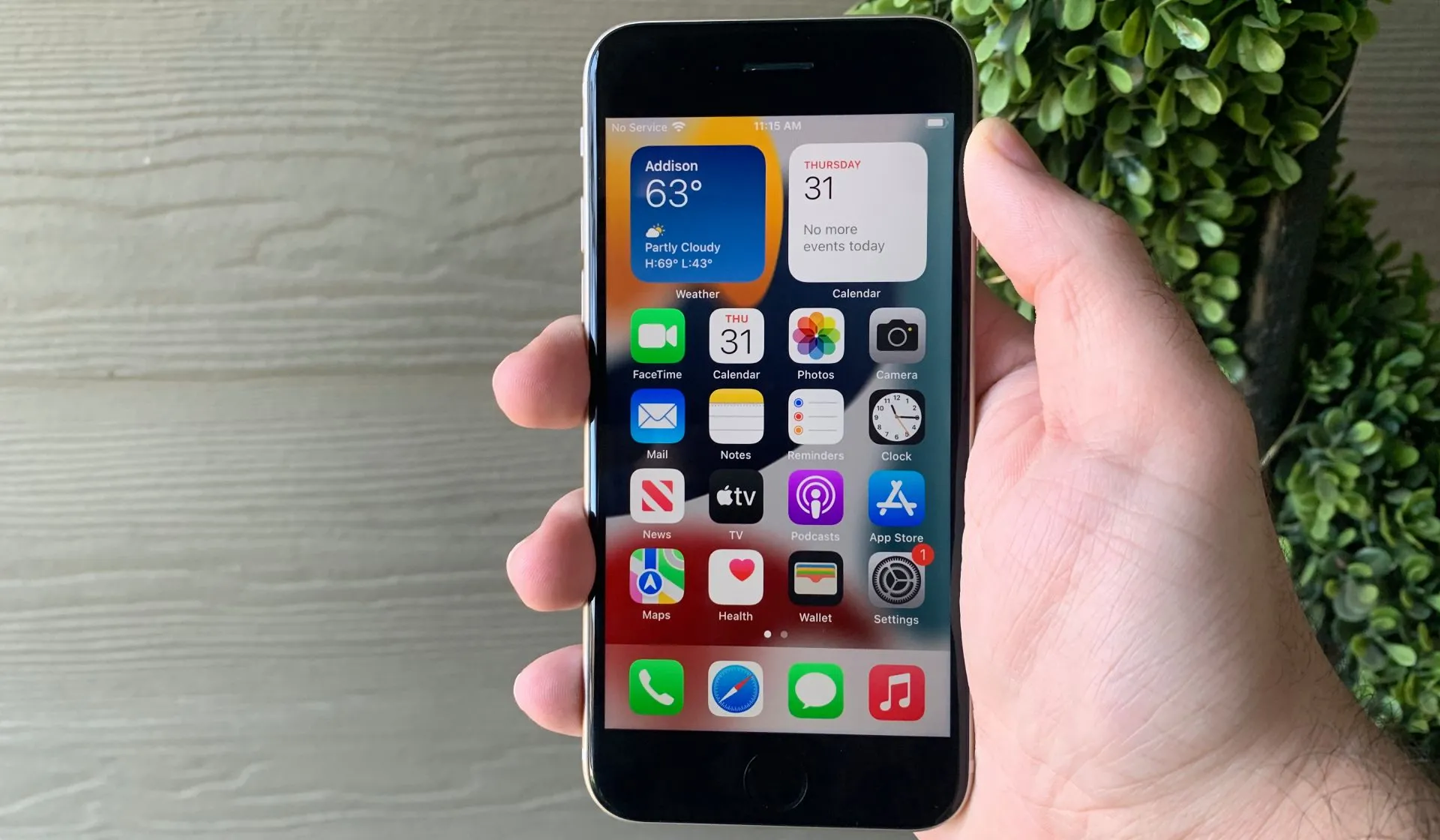 Một người đang cầm chiếc iPhone SE 2022 màu trắng, hiển thị màn hình chính