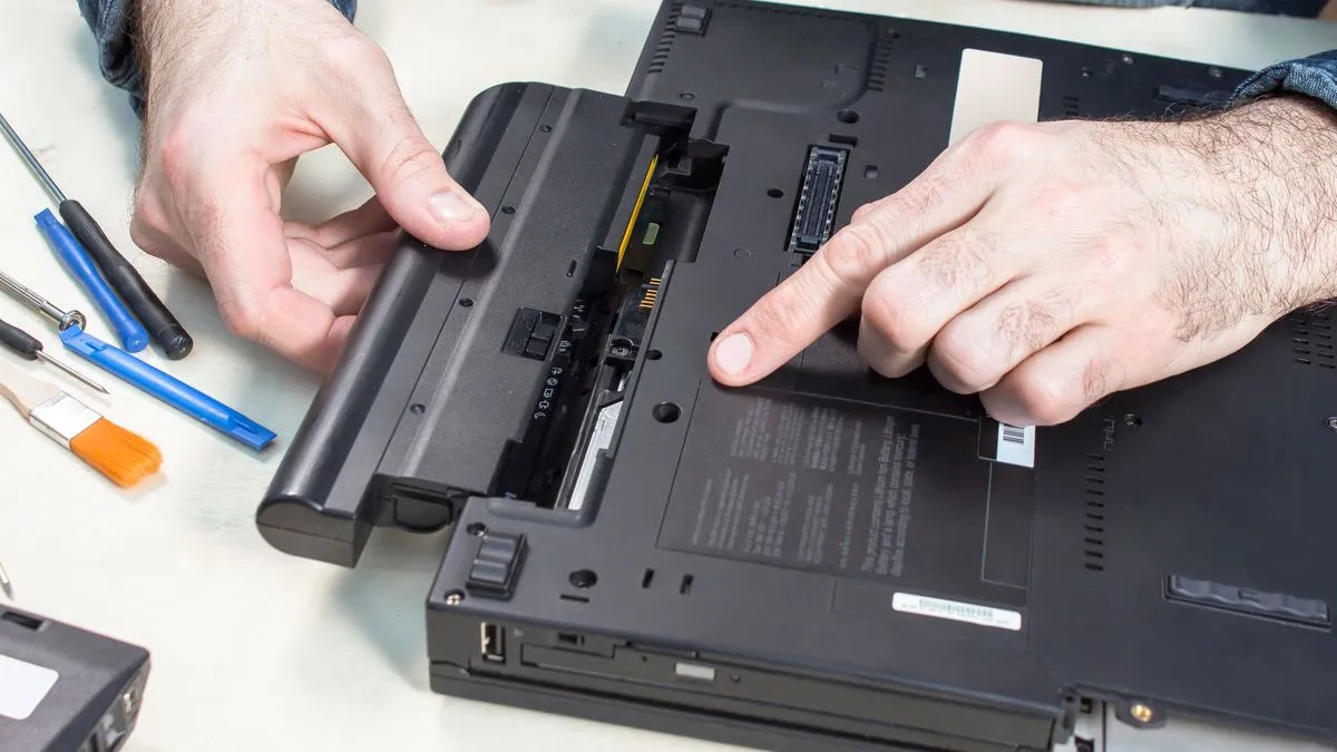 Một người đang kiểm tra hoặc tháo pin laptop, nhấn mạnh tầm quan trọng của việc sửa chữa và bảo dưỡng pin đúng cách để tránh hư hỏng.