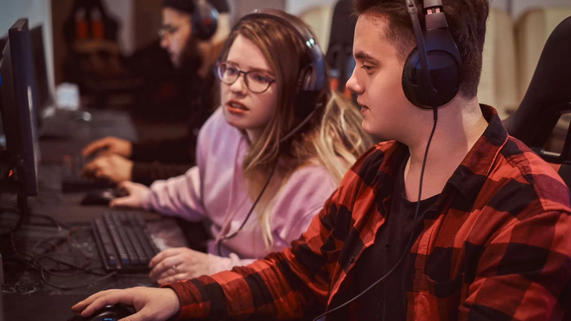 Một nhóm game thủ tuổi teen đang chơi trò chơi điện tử nhiều người chơi trên PC trong một câu lạc bộ game.