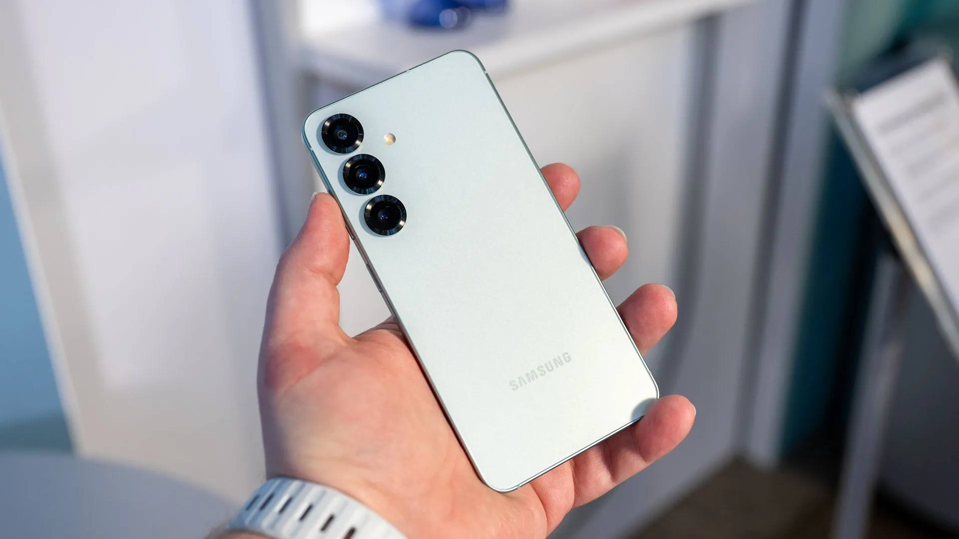 Người dùng cầm điện thoại Samsung Galaxy S25 và nhìn vào cụm camera sau, nhấn mạnh thiết kế camera trên thiết bị.