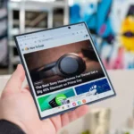 Người dùng đang cầm Samsung Galaxy Z Fold 7 mở ra, hiển thị trang web How-To Geek trên màn hình chính