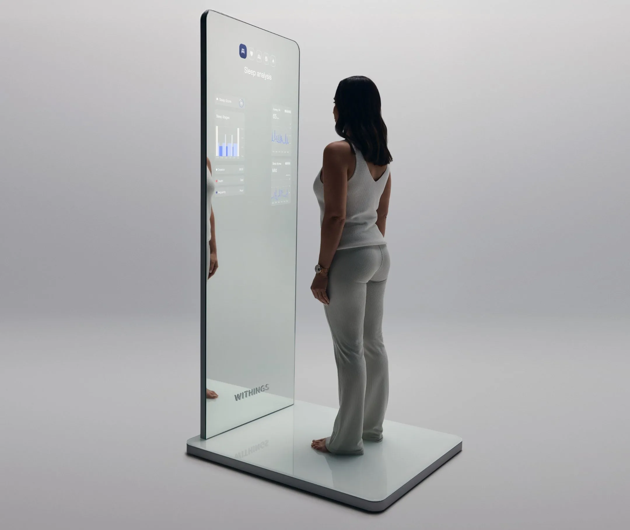 Người dùng đứng trên đế cảm biến Withings Omnia, xem các chỉ số sức khỏe hiển thị trên màn hình gương toàn thân.