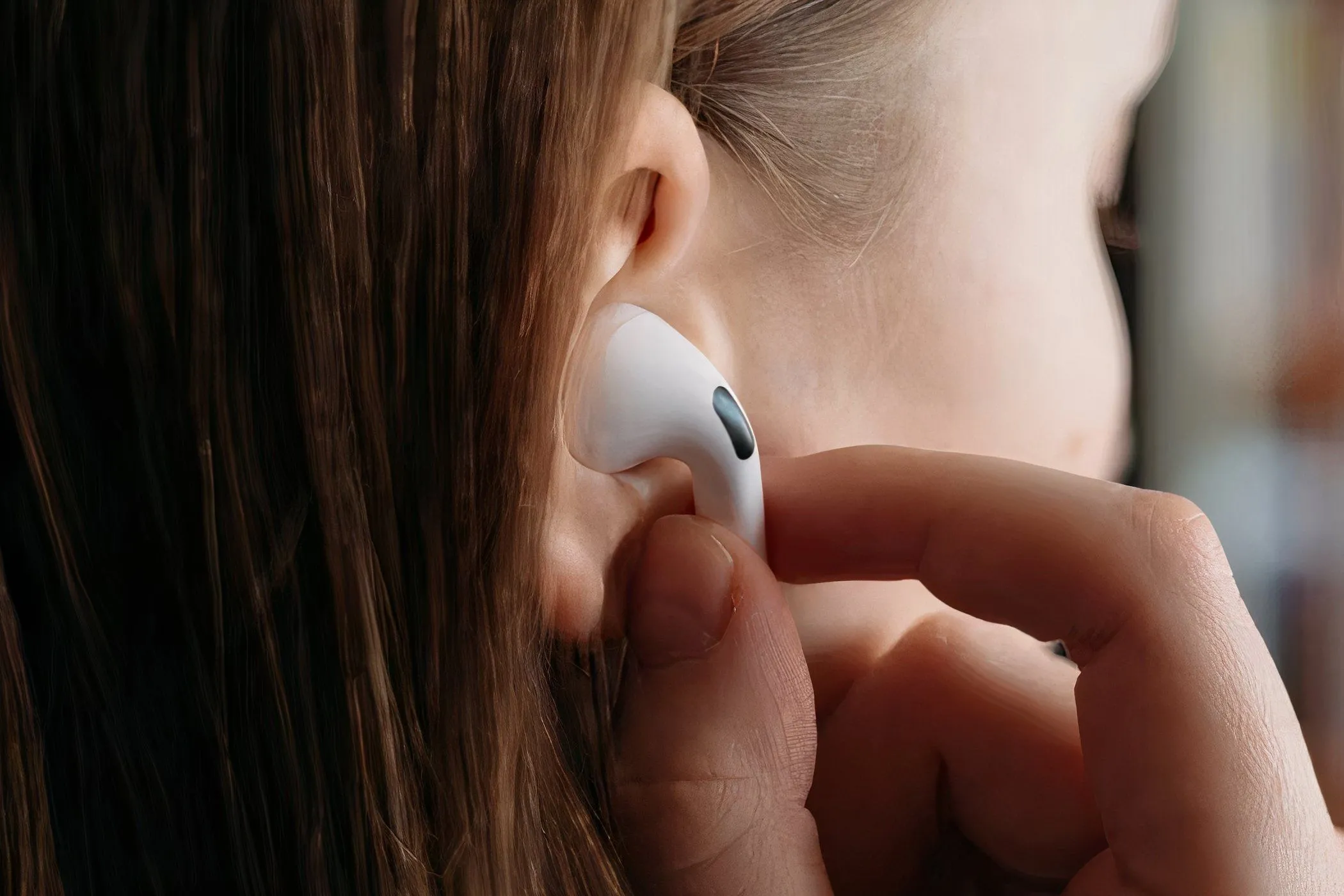 Người phụ nữ đang đeo AirPods Pro vào tai, tượng trưng cho sự tiện lợi và trải nghiệm liền mạch mà tai nghe không dây của Apple mang lại cho người dùng.