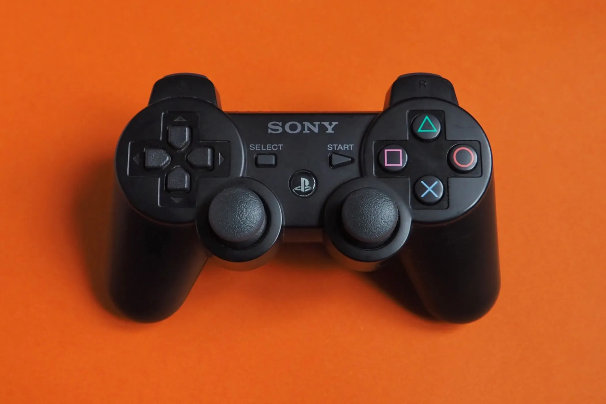 Tay cầm Sony PlayStation 2 DualShock với hai cần analog và tính năng rung, biểu tượng của hệ thống điều khiển game hiện đại được chuẩn hóa từ thời PS2.